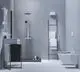 Badezimmer mit grauer Wand und Boden, ausgestattet mit Duschbereich, Waschbecken und moderner Ideal Standard Waschtischarmatur. Handtücher hängen an einem Regal.